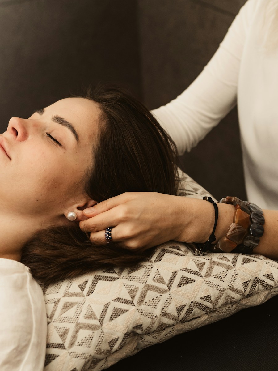 Therapist gently touching woman's ear during treatment